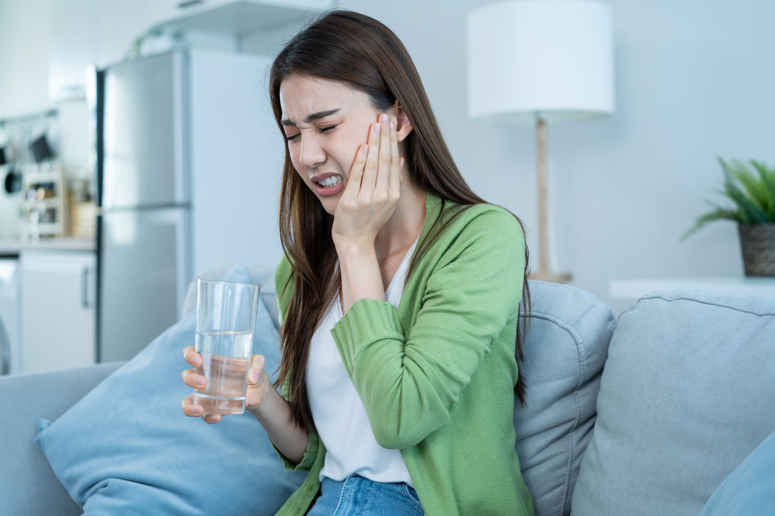 Woman experiencing sudden tooth pain while holding her jaw, a sign she may need to see a dentist near her