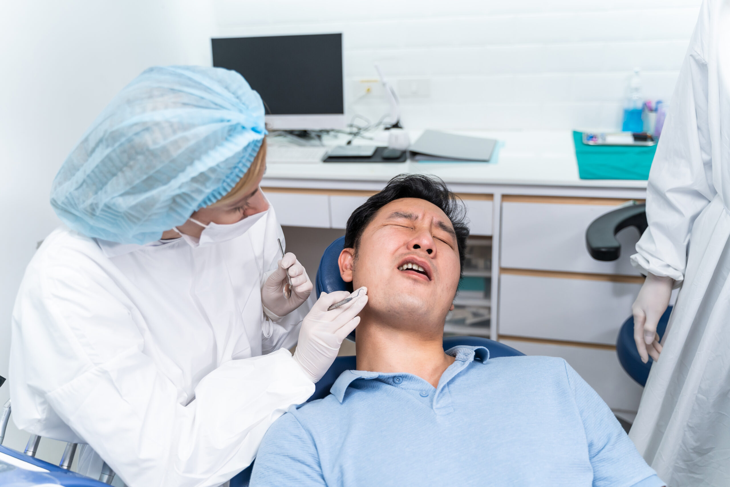 Dentist examining patient experiencing discomfort after oral surgery, highlighting post-surgical care and infection concerns