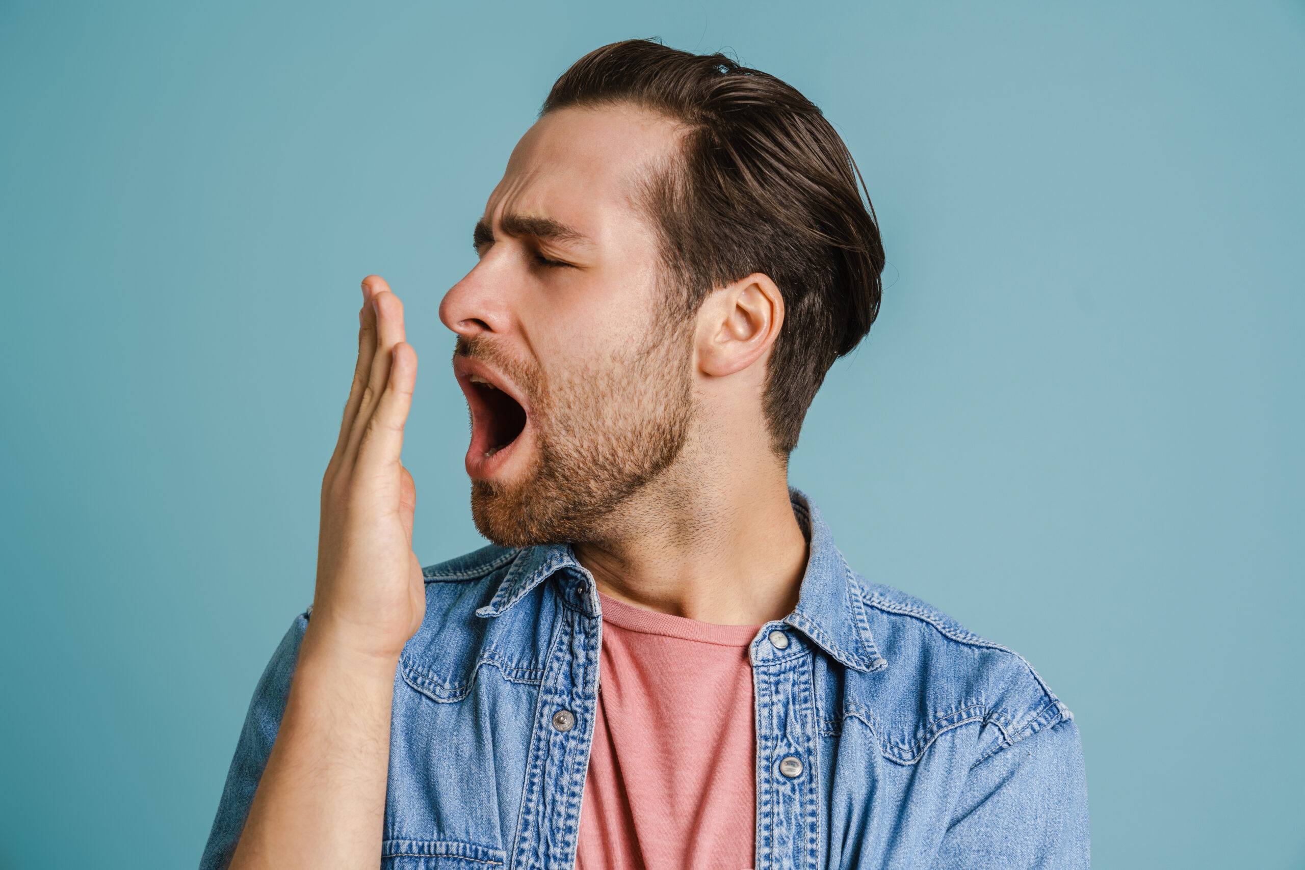 Man checking his breath by covering mouth, showing concern about bad breath after brushing